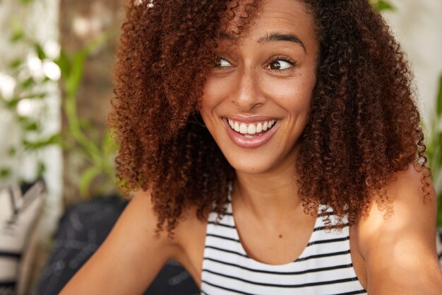 Zufriedene begeisterte Afroamerikanerin hat knackiges Haar