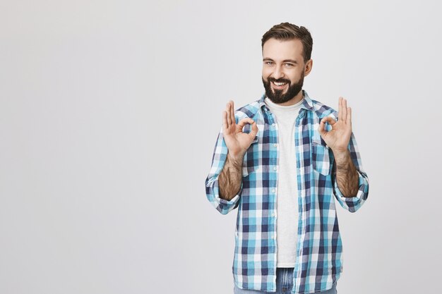 Zufriedene erwachsene bärtige Kerl zeigen okay Gesten