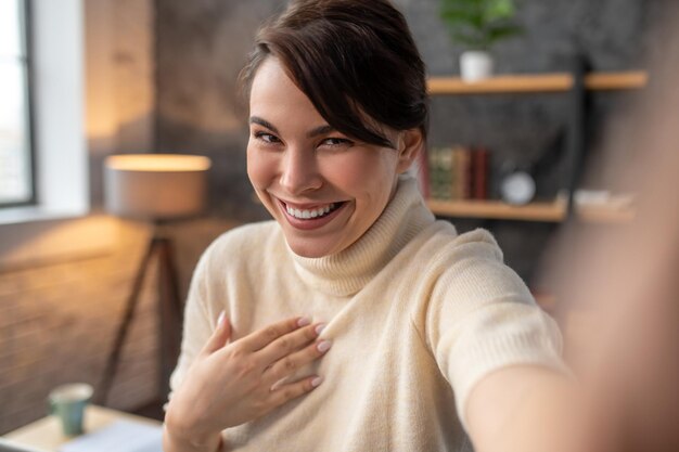 Zufriedene Frau, die über Skype auf ihrem Gadget kommuniziert