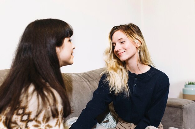 Zufriedene Frauen, die auf Couch plaudern