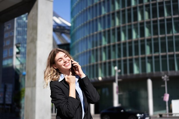 Zufriedene Geschäftsfrau feiert auf der Straße im Gespräch mit dem Handy und erhält gute Nachrichten auf Abruf