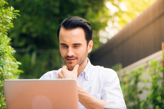 Zufriedene Geschäftsmann arbeitet am Laptop mit Internet Wireless