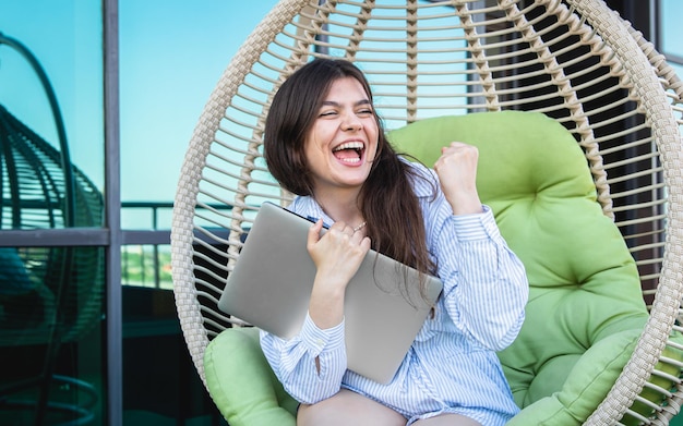 Zufriedene junge Frau nach einem Arbeitstag mit einem Laptop in einer Hängematte