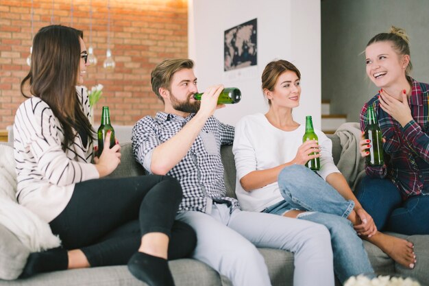 Zufriedene junge Leute, die zu Hause Biere genießen