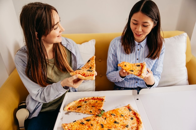 Zufriedene junge Mädchen, die Pizza haben