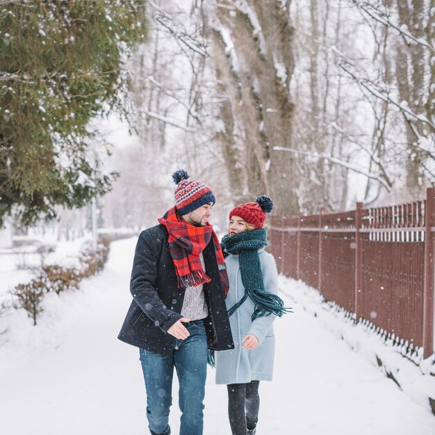Zufriedene junge Paare, die auf schneebedeckte Straße laufen