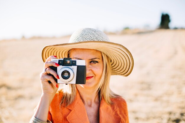 Zufriedene modische Frau mit Fotokamera