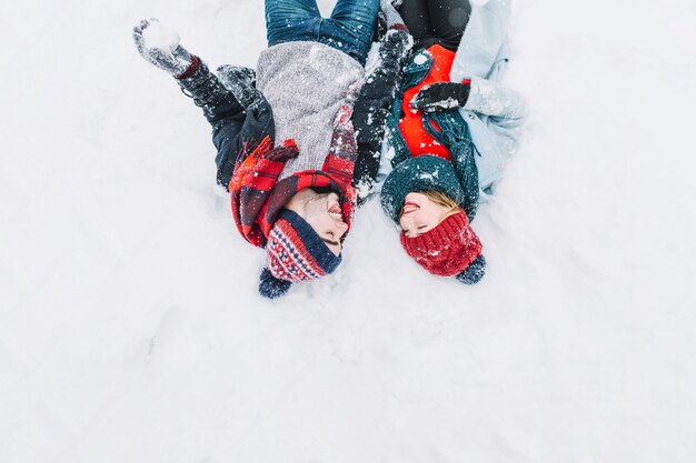 Zufriedene Paare, die auf Schnee liegen