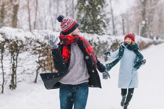 Zufriedene Paare, die Schneebälle im Park spielen