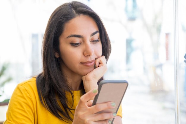 Zufriedene schöne junge Frau, die Smartphone verwendet