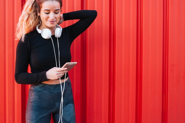 Zufriedene Sportlerin, die Telefon auf Straße verwendet