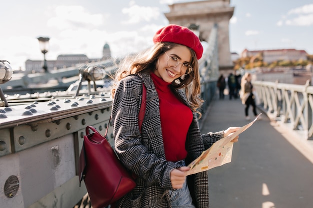 Kostenloses Foto zufriedene weibliche reisende im eleganten outfit, das urlaub in frankreich verbringt