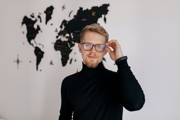 Zufriedener Mann mit der Arbeit. Glücklicher junger Mann, der am Laptop arbeitet, während er an seinem Arbeitsplatz im Büro aufwirft.