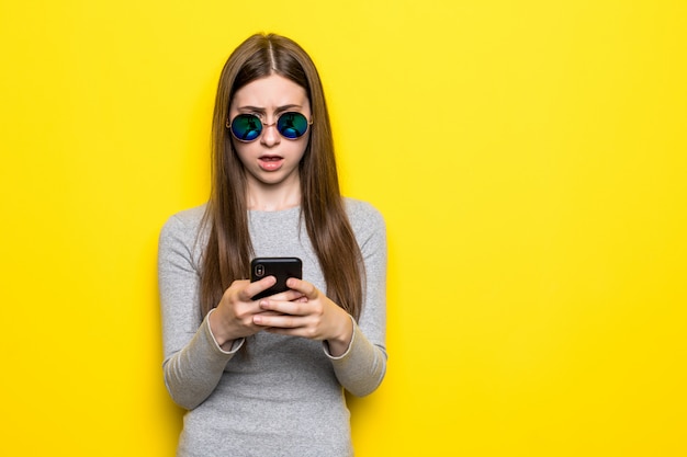 Zufriedener Teenager mit langen Haaren, hält modernes Handy, blättert durch soziale Netzwerke