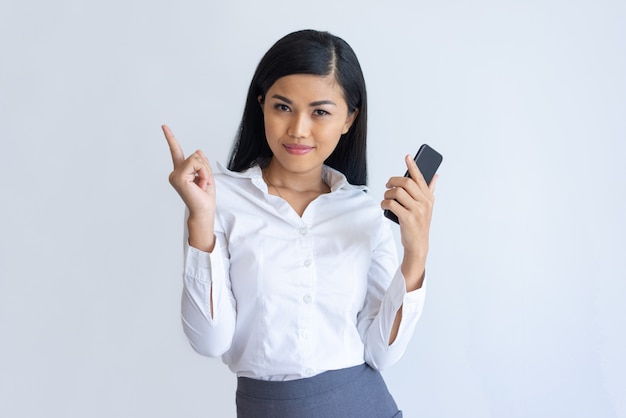 Zufriedenes asiatisches Mädchen mit dem Telefon, das Idee hat