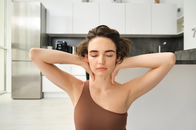 Kostenloses Foto zuhause sport und wohlbefinden junge brünette frau in sportkleidung, die zu hause bleibt und bewusst yoga macht