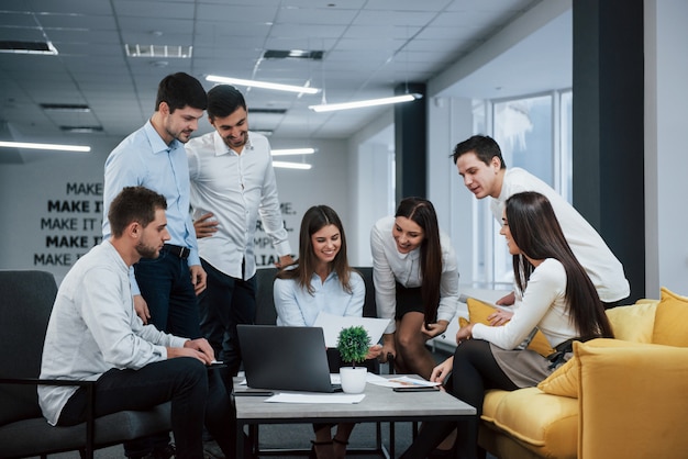 Zum Erfolg. Eine Gruppe junger Freiberufler im Büro unterhält sich und lächelt