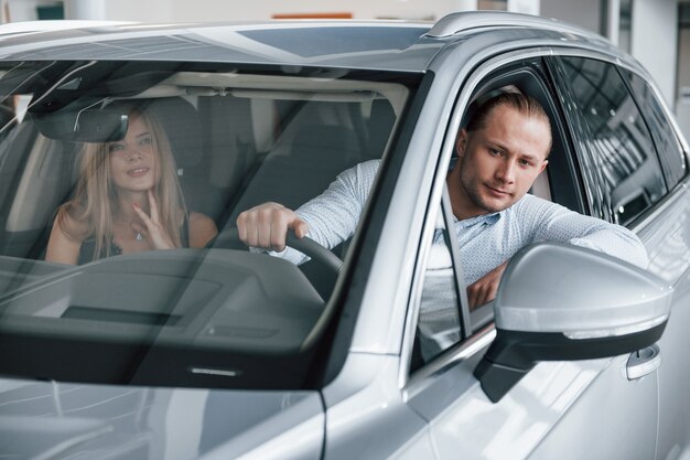 Zurück gehen. Positiver Manager, der der Kundin die Merkmale des neuen Autos zeigt