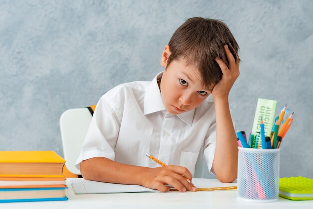 Zurück zur Schule. Glücklicher lächelnder Student zeichnet am Schreibtisch.