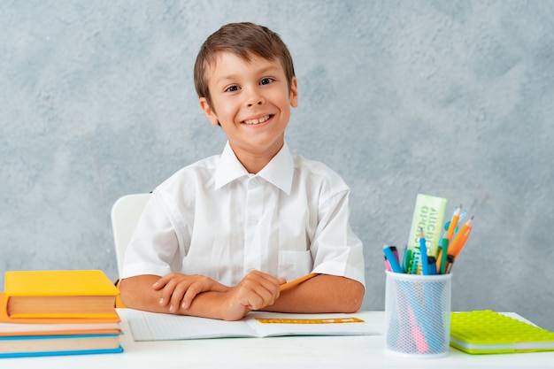 Zurück zur Schule. Glücklicher lächelnder Student zeichnet am Schreibtisch.