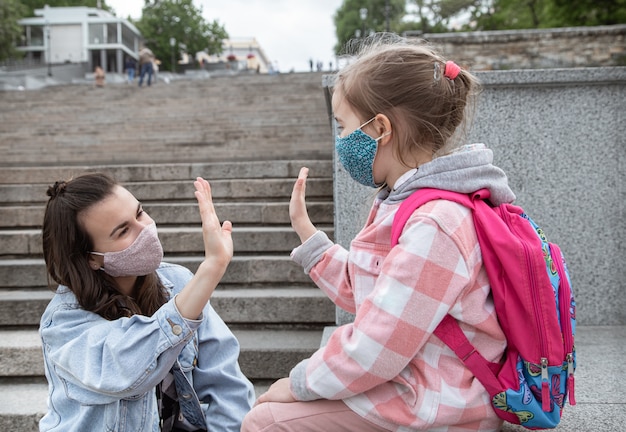 Zurück zur Schule. Kinder mit Coronavirus-Pandemie gehen in Masken zur Schule. Freundliche Beziehungen zur Mutter. Kindererziehung.