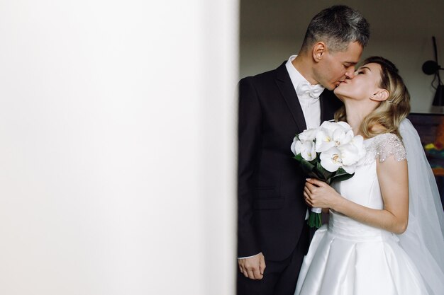 Zusammengehörigkeit. Bräutigam küsst die zarte Stellung der Braut in einem Hotelzimmer