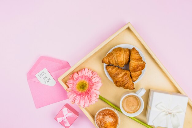 Zusammensetzung der Bäckerei, der Blume und des Geschenks auf Behälter nahe Umschlag mit Umbau