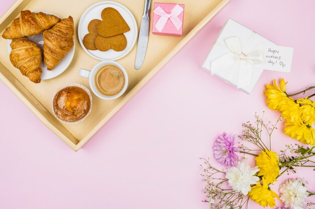 Zusammensetzung der Bäckerei und der Schale auf Tellersegment nahe Geschenk und Blumen