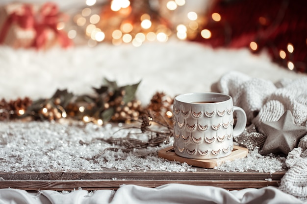 Zusammensetzung mit Weihnachtsbecher mit heißem Getränk auf unscharfem abstraktem Hintergrundkopierraum.