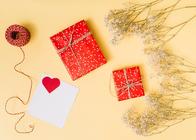 Zusammensetzung von Geschenkkartons, Ornament Herz auf Papier, Pflanzen und Fäden