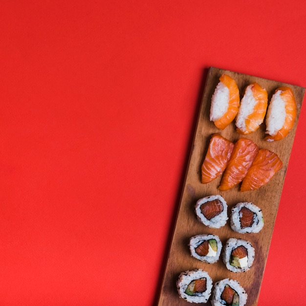 Zusammenstellung von Sushi auf hölzernem Behälter gegen roten Hintergrund mit Kopienraum für das Schreiben des Textes