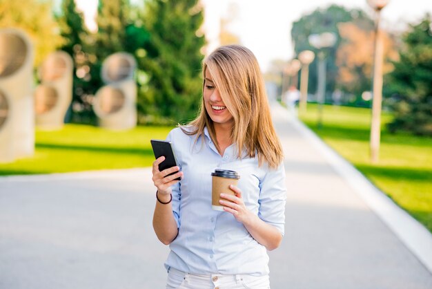 Zuversichtlich Frauen lesen Informationen über Finanzen Nachrichten beim Gehen in Unternehmen Flur während der Arbeit Pause, erfolgreiche Geschäftsfrau schriftlich SMS-Nachricht ihre Client während geht mit Sekretärin zu Büro