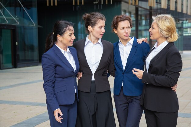 Zuversichtlich Geschäftsfrauen, die zusammen draußen stehen, umarmen und sprechen. Geschäftsfrauen tragen Anzüge Treffen in der Stadt. Weibliches Team und Teamwork-Konzept