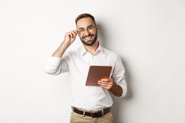 Zuversichtlich Geschäftsmann, der auf digitalem Tablett arbeitet, glücklich lächelnd, stehend