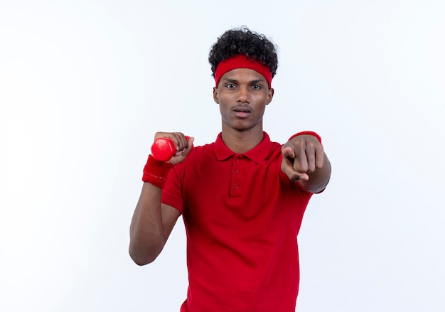 Zuversichtlich junger afroamerikanischer sportlicher Mann, der Haarband und Armband hält Hantel hält und Sie Geste lokalisiert auf weißem Hintergrund zeigt