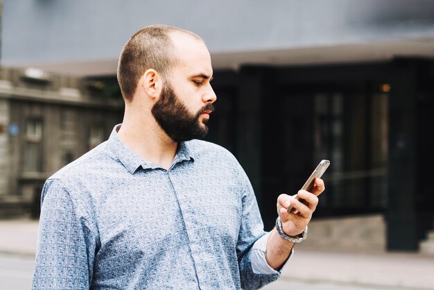 Zuversichtlich mit Telefon auf städtischen Hintergrund