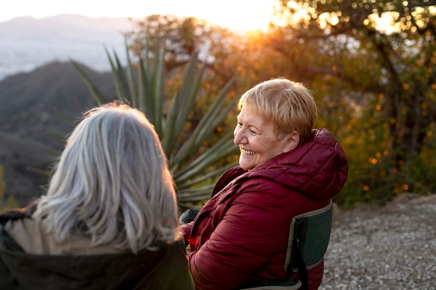 Zwei ältere Frauen auf einem Naturausflug sitzen auf Stühlen und genießen ihre Zeit