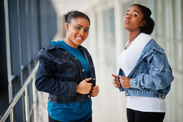 Zwei afrikanische Freundinnen in Jeansjacke posierten gemeinsam im Innenbereich