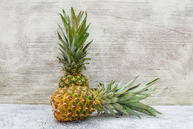 Zwei aromatische Ananas an grauer Wand und schmuddeliger Seitenansicht.