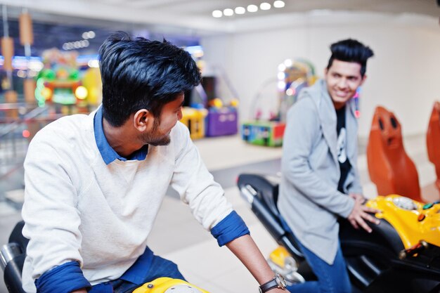 Zwei asiatische Jungs treten auf einem Speedrider-Arcade-Motorrad-Rennsimulator an