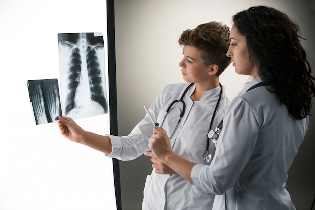 Zwei attraktive junge Doktoren, die Röntgenstrahlergebnisse betrachten