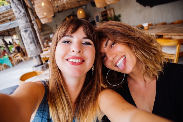 Zwei europäische kaukasische Freundinnen mit natürlichem Make-up und kurzen Haaren machen Selfie im Sommercafé