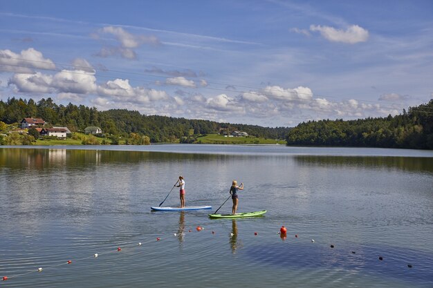Zwei Frauen, die ein Stand-Up-Paddle-Board im Smartinsko-See in Slowenien reiten