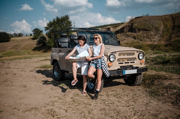 Zwei Frauen, die Karte während der Fahrt mit dem Auto überprüfen