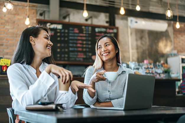 Zwei Frauen, die mit einem Laptop in einer Kaffeestube sitzen und arbeiten