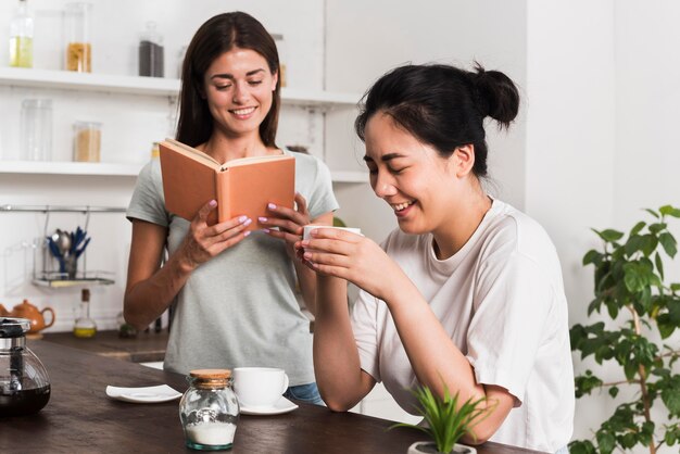 Zwei Frauen in der Küche lesen und trinken Kaffee