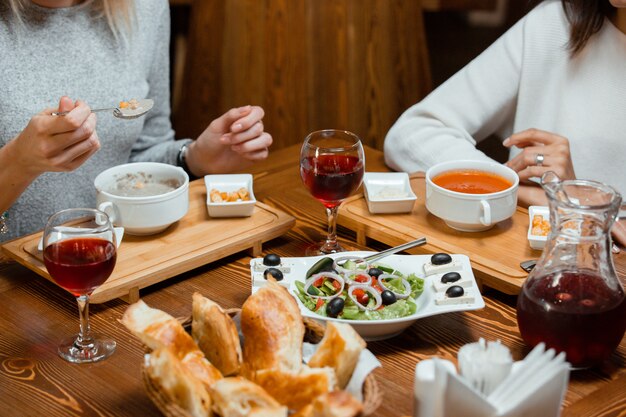 zwei Freunde essen Suppe und Salat, während sie Kompott trinken