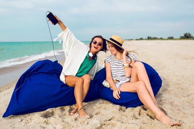 Zwei Freunde sitzen auf Strandkissen und haben Spaß