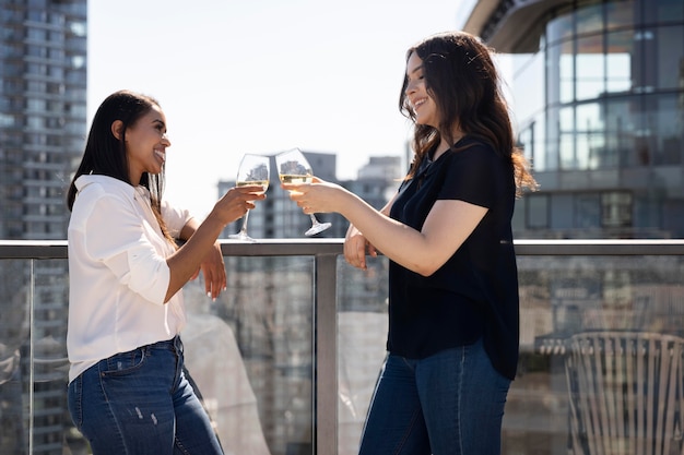 Zwei Freundinnen auf einer Dachterrasse, die Wein trinken und sich unterhalten