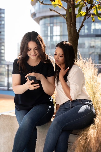 Zwei Freundinnen auf einer Dachterrasse mit Smartphone